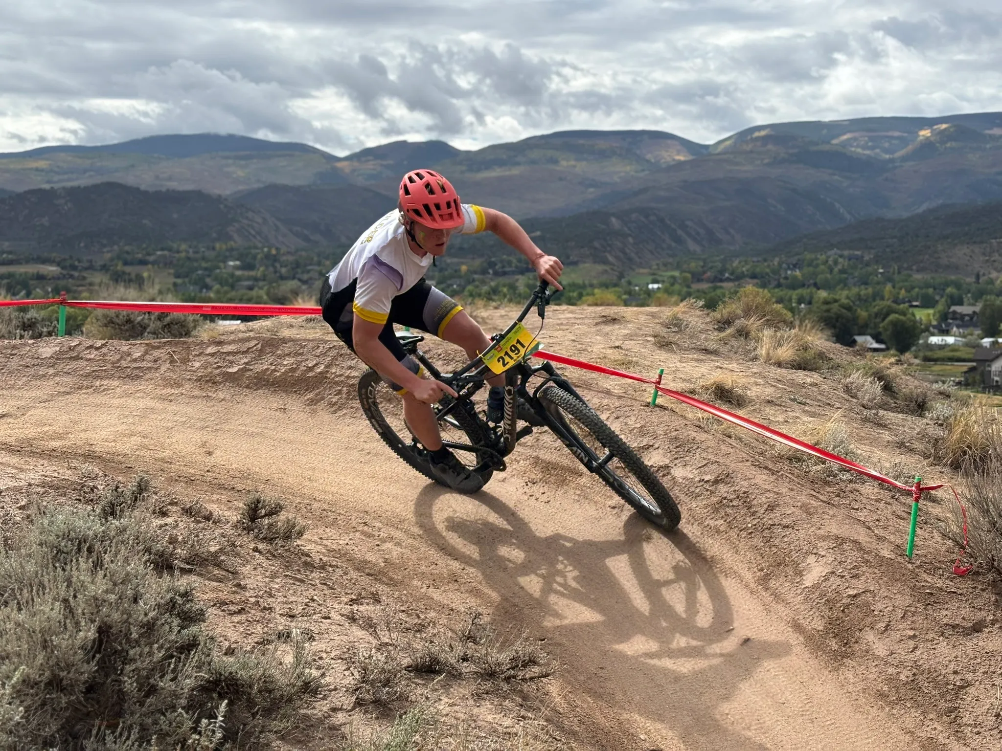 A Boulder High rider leaning into a corner on a singletrack with mountains behind